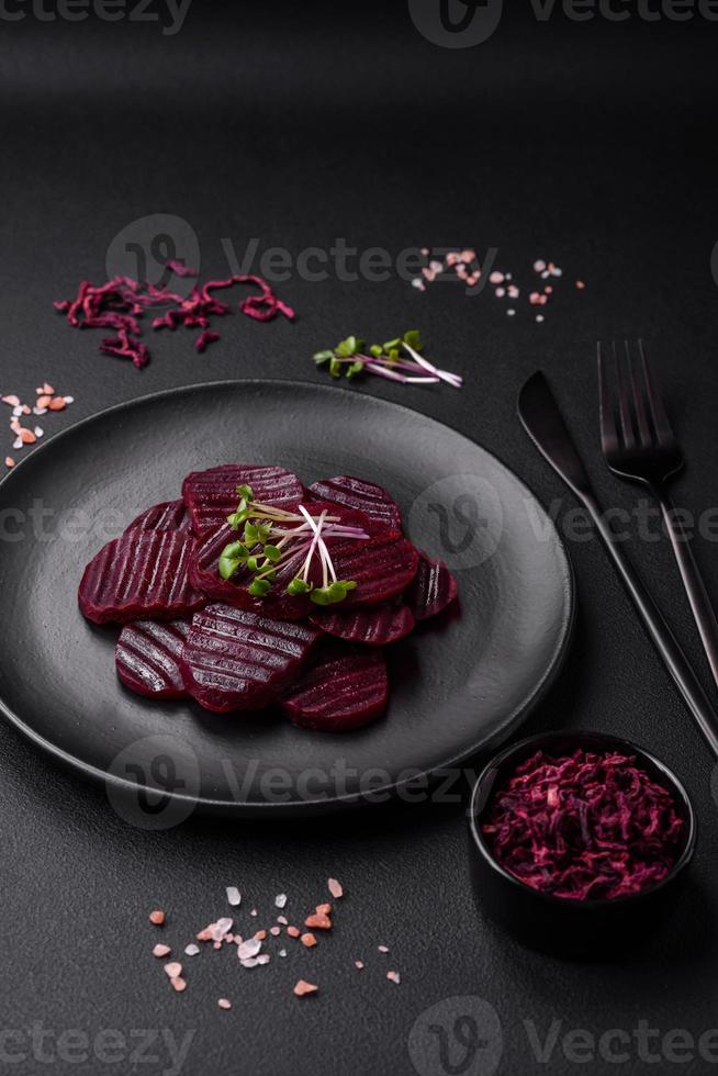 Delicious healthy boiled ruby-colored beets sliced  on a black plate photo