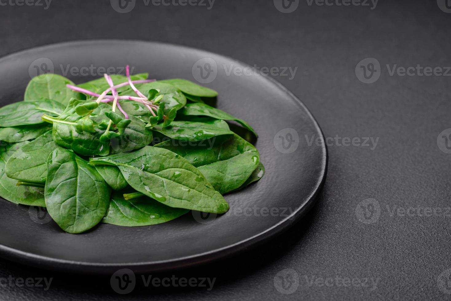 Fresh green spinach leaves on a black ceramic plate photo