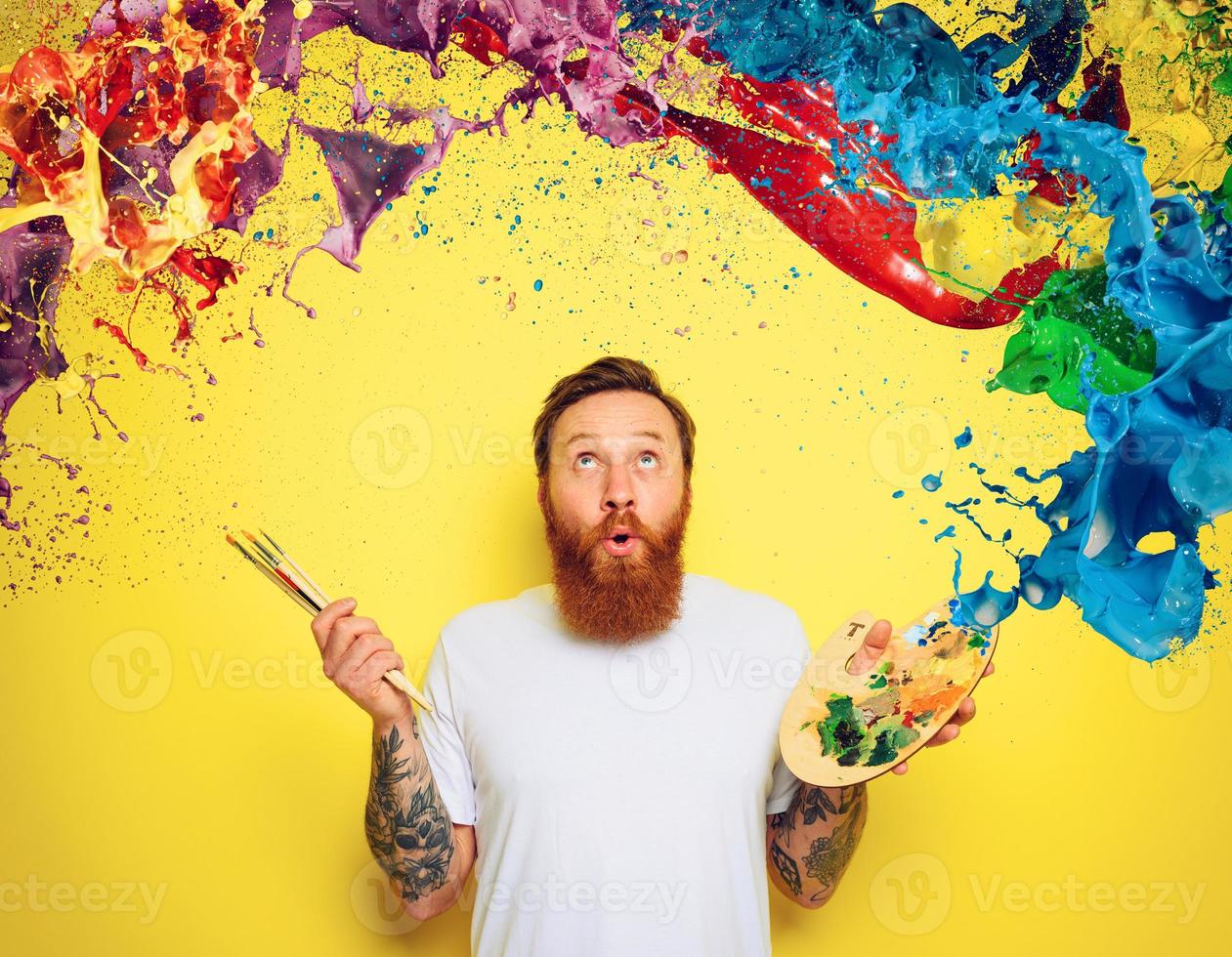 Amazed man with beard and tattoo is ready to draw with brushes photo