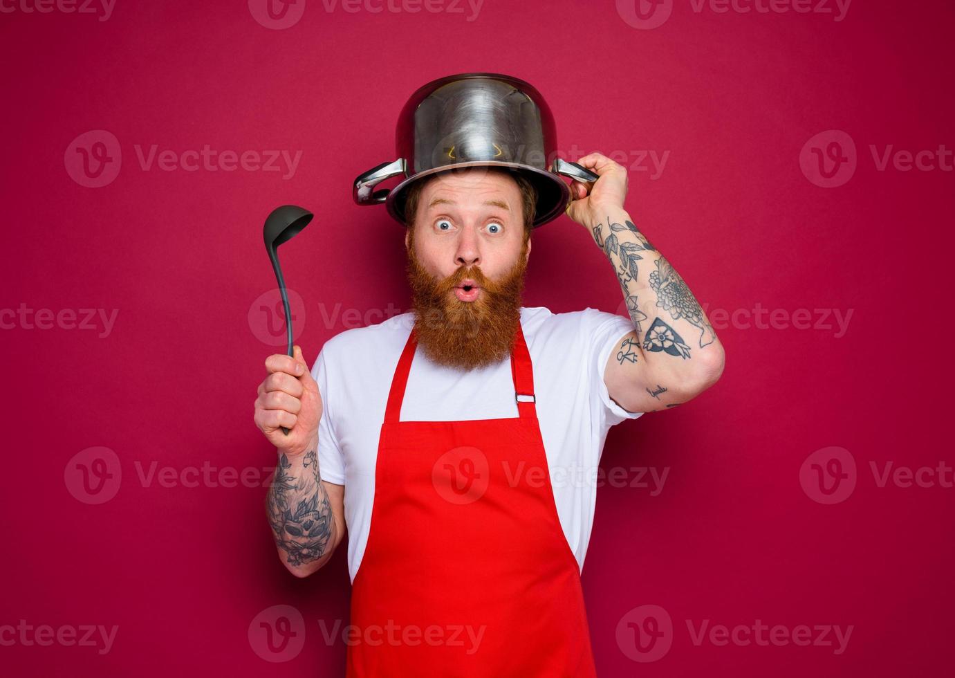 wondered chef with beard and red apron plays with pot photo