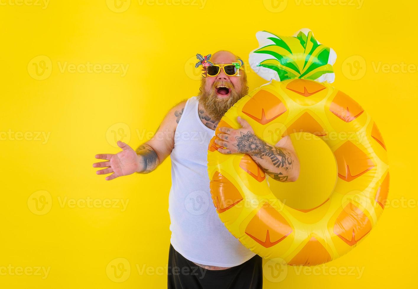 Fat amazed man with wig in head is ready to swim with a donut lifesaver photo
