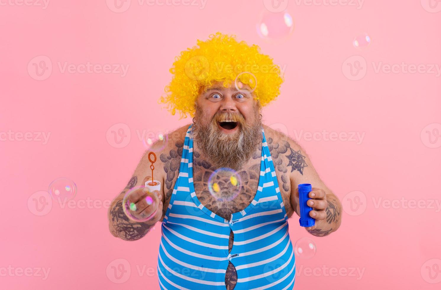 Amazed man with yellow wig in head play with bubbles soap photo