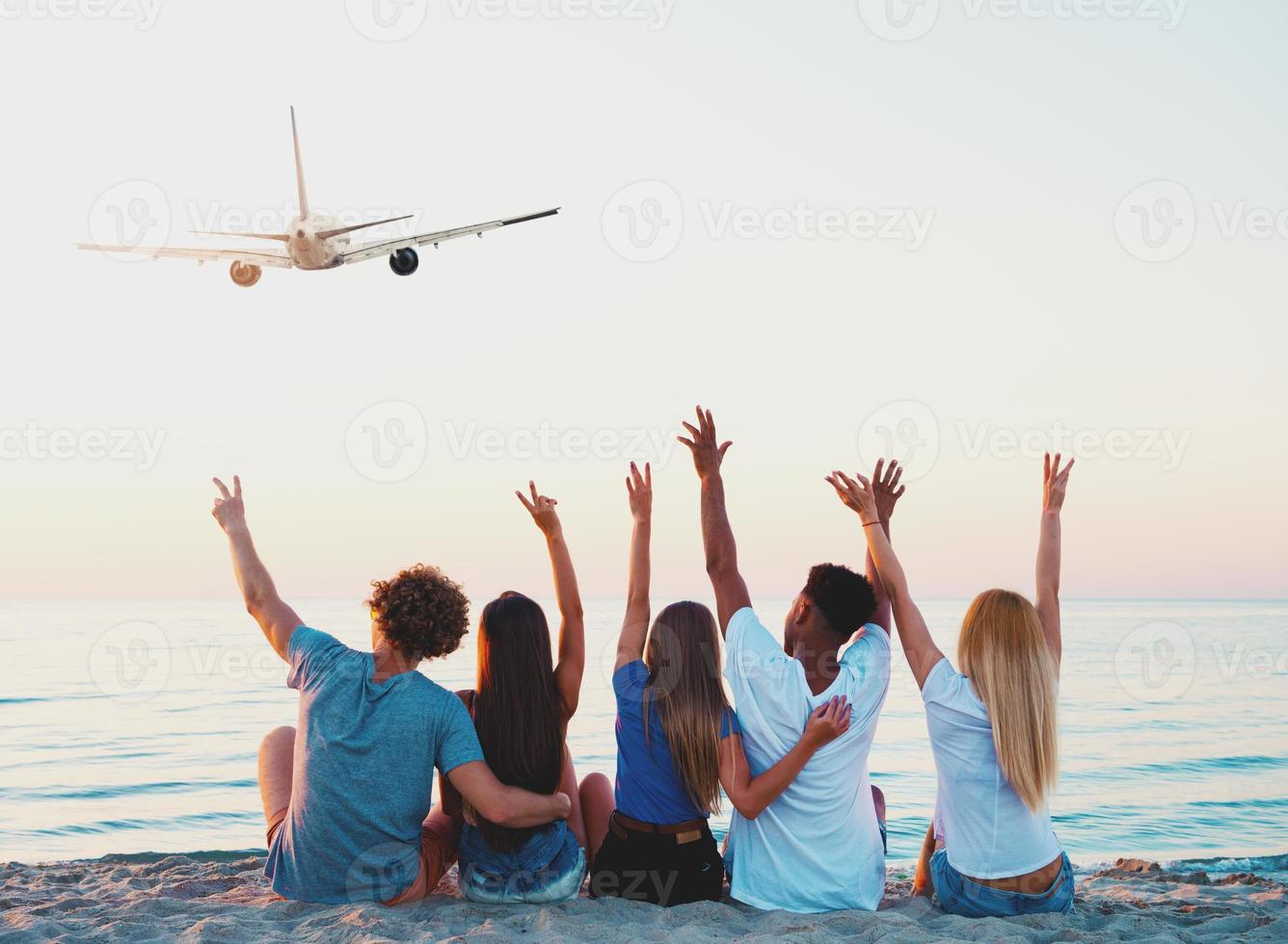 Group of friends having fun on the beach with flying aircraft photo