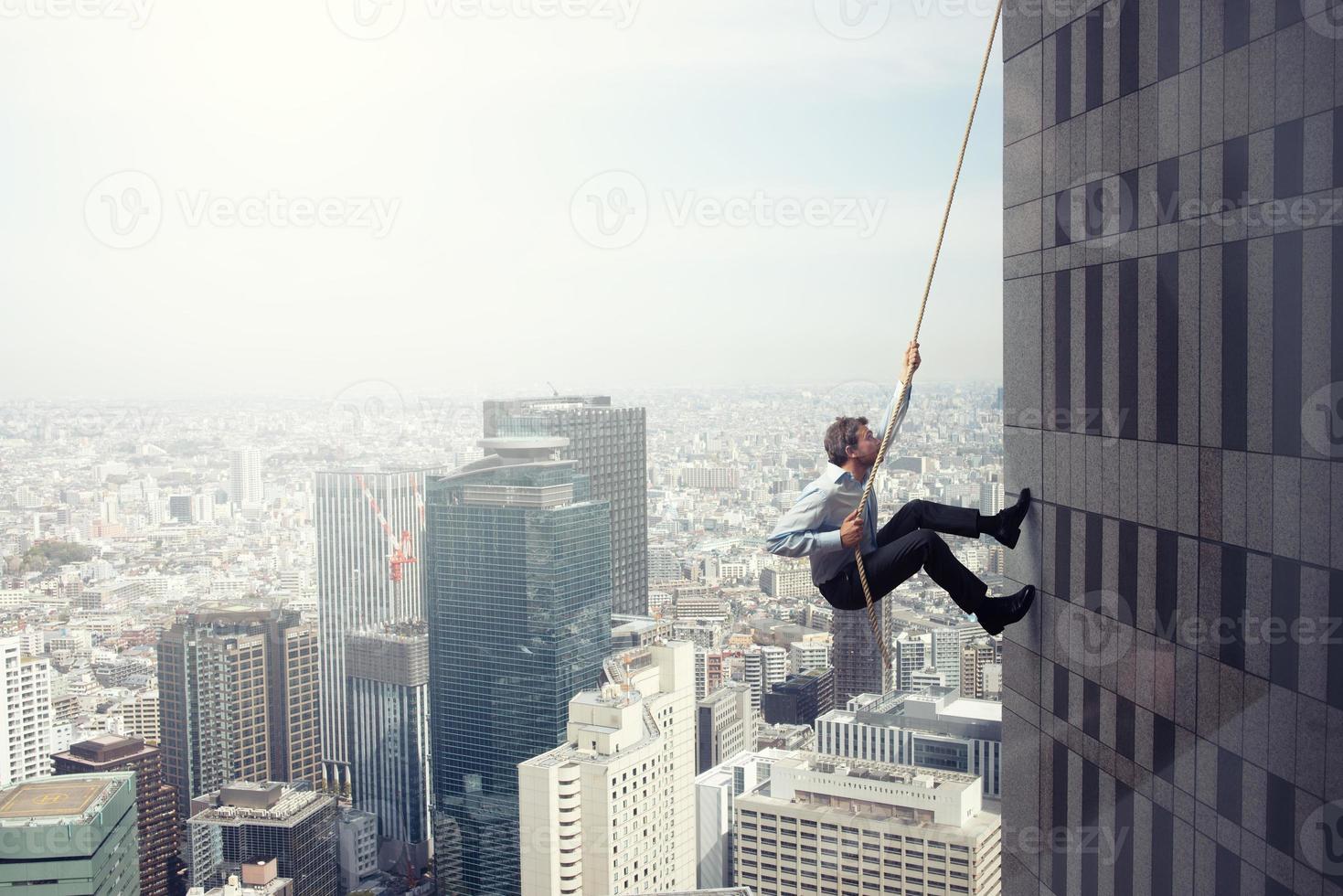 Businessman climbs a building with a rope. Concept of determination photo