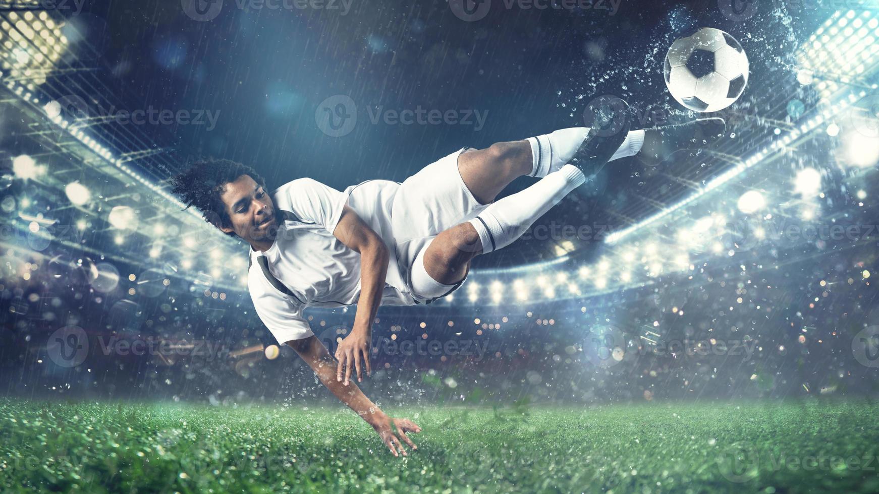 Soccer striker hits the ball with an acrobatic kick in the air at the stadium photo