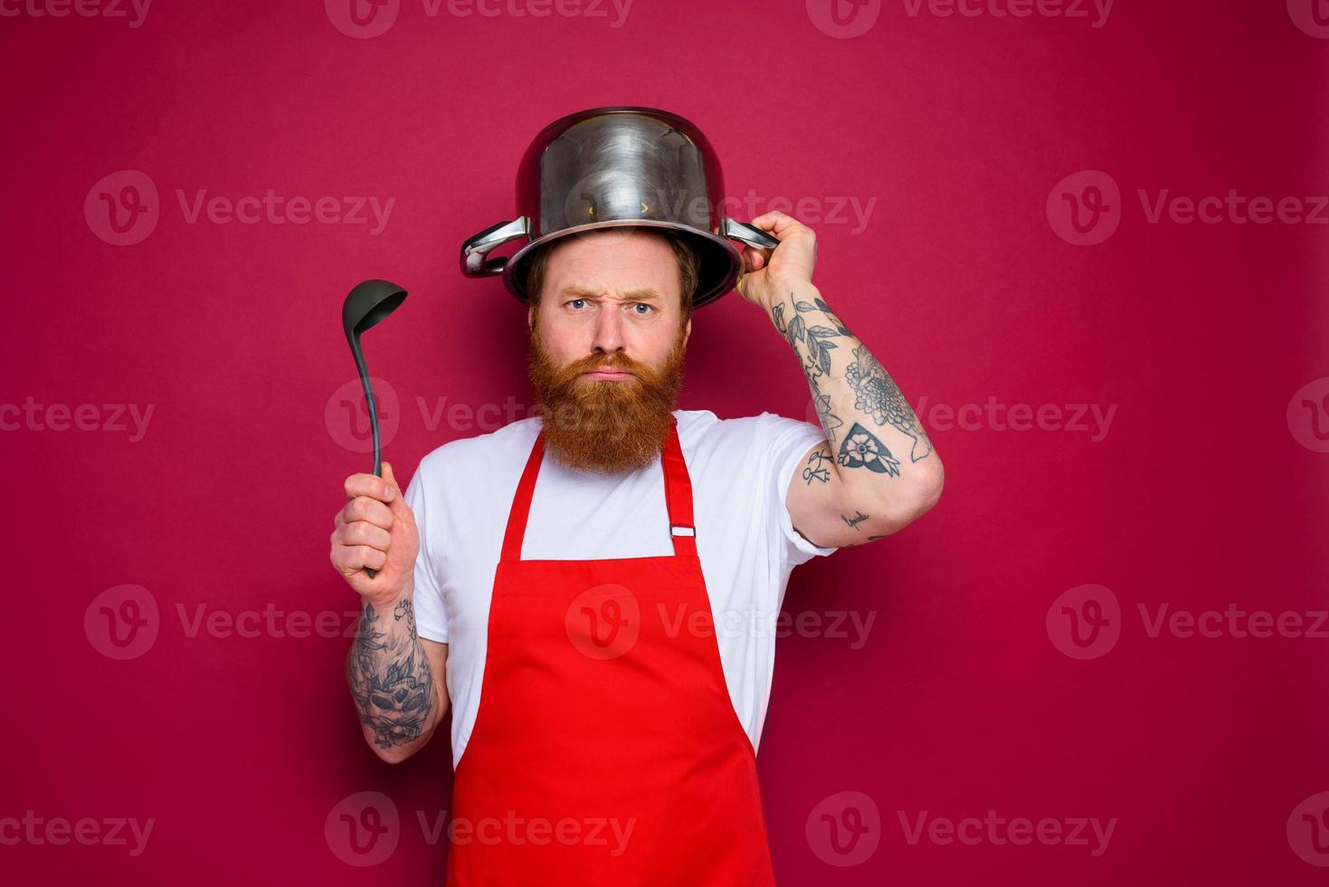 unhappy chef with beard and red apron plays with pot photo