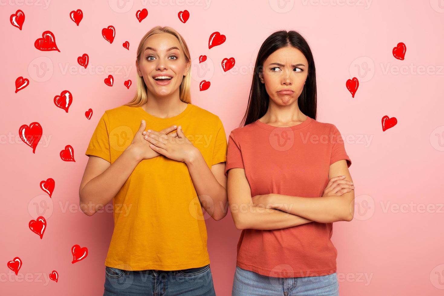 Friends receives likes and hearts from social network. But the blonde is happy and the brunette is not. Pink background photo