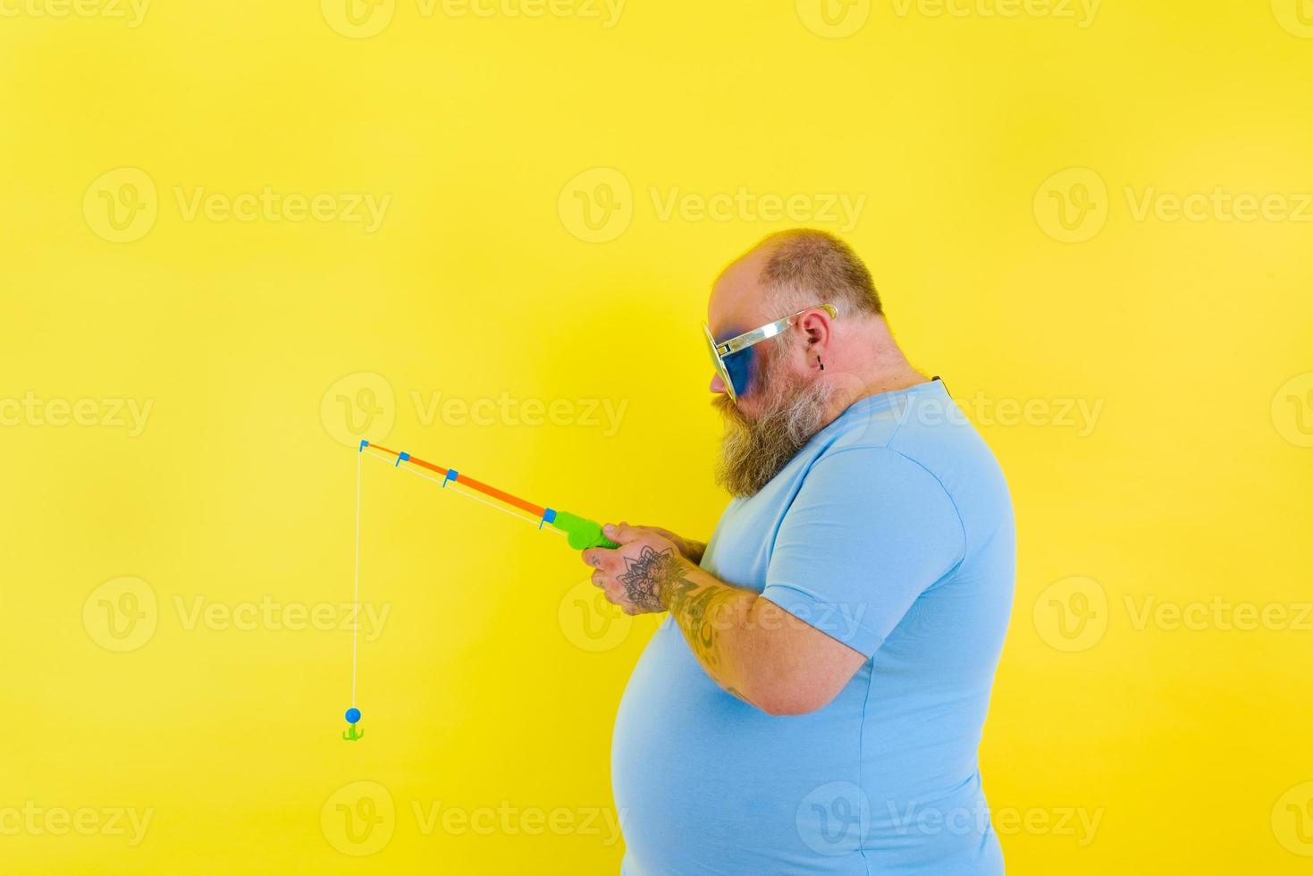 Fat man with beard and sunglasses is unhappy with the fishing rod photo