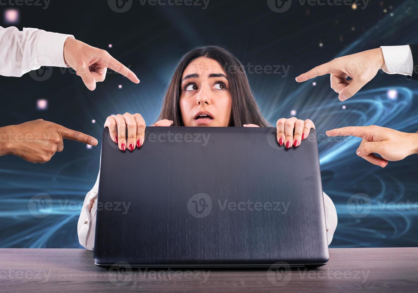 Afraid girl hides herself rear the laptop. She is victim of cyberbullying photo