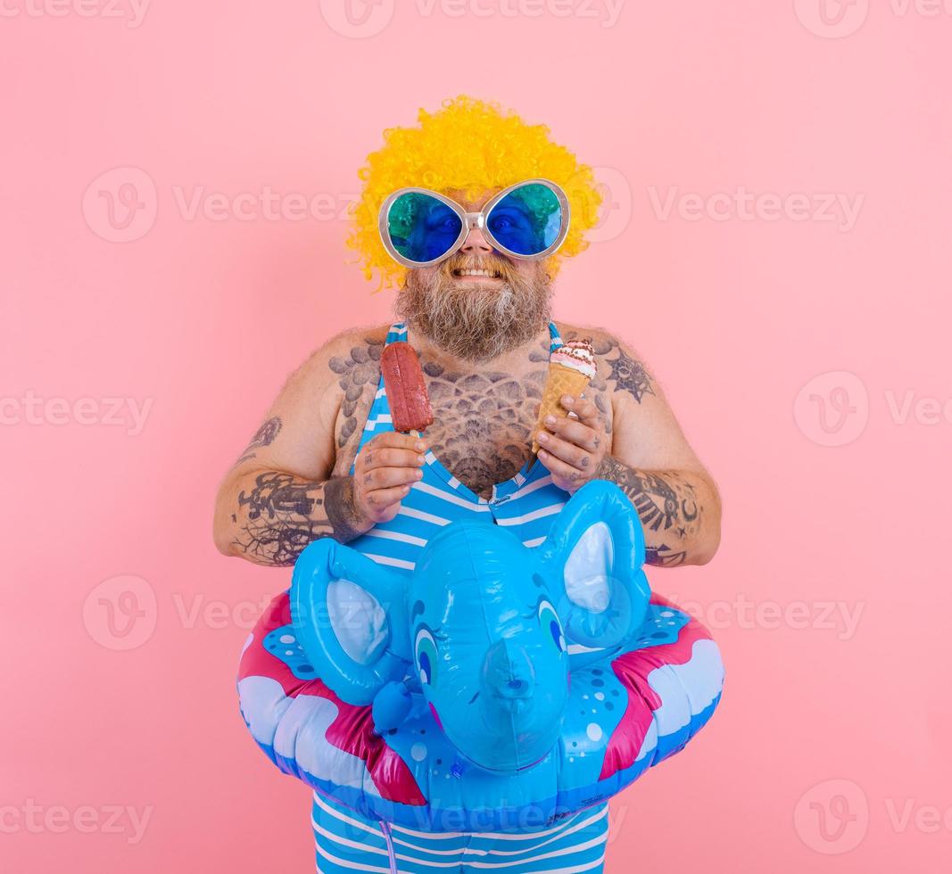 Fat man with beard and wig eats a popsicle and an icecream photo