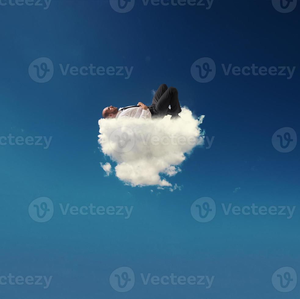 Stressed businessman relaxing on a soft cloud photo