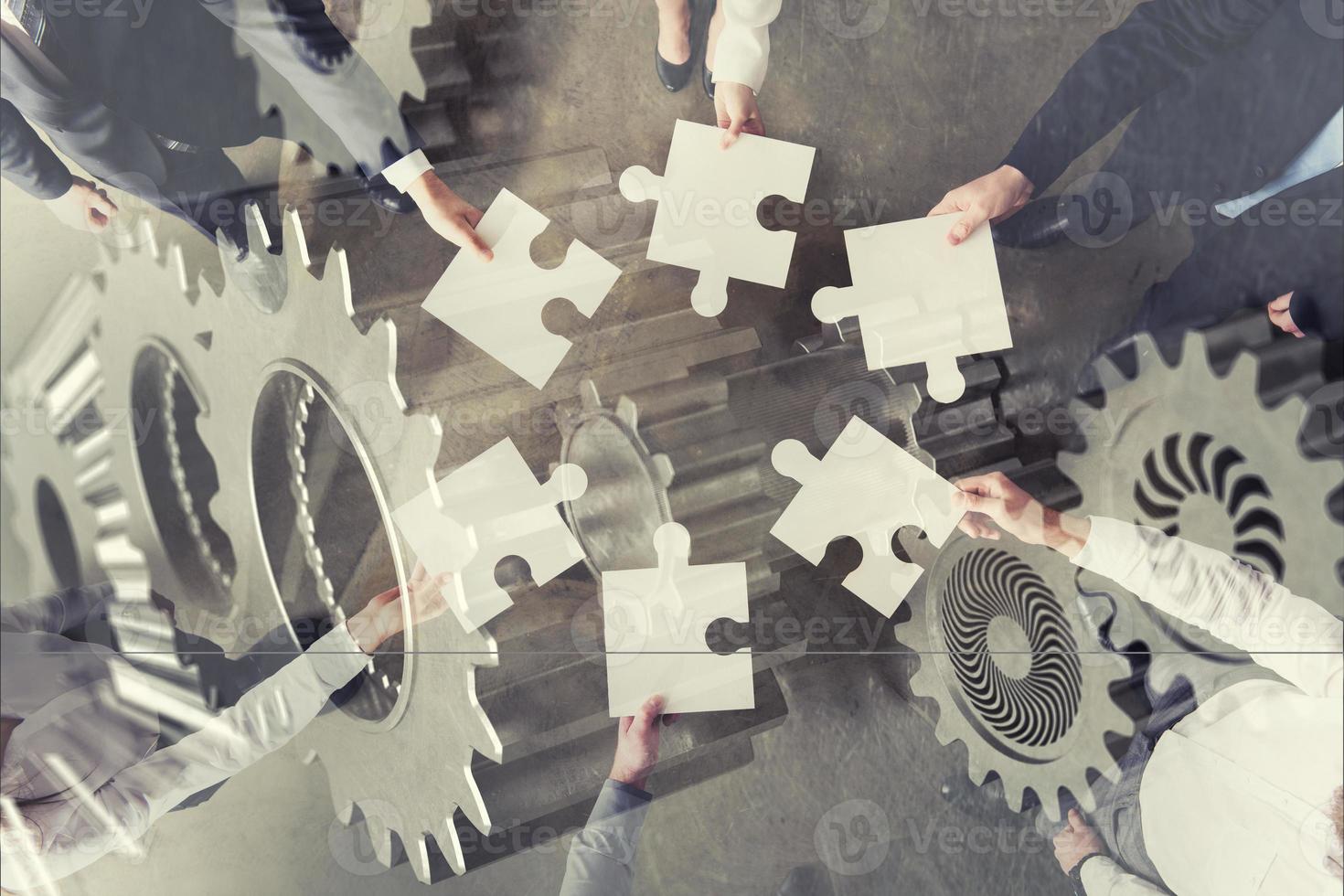 Teamwork of partners. Concept of integration and startup with puzzle pieces and gear overlay. double exposure photo