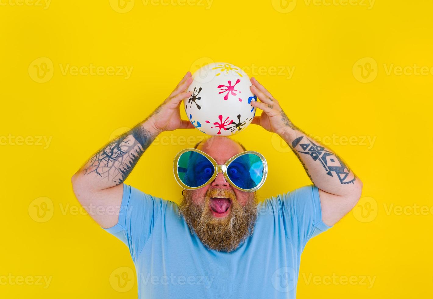 Fat man with beard and sunglasses have fun with a ball photo