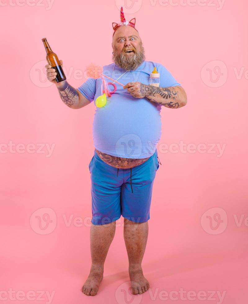 Fat happy man acts like a happy baby but drinks beer photo