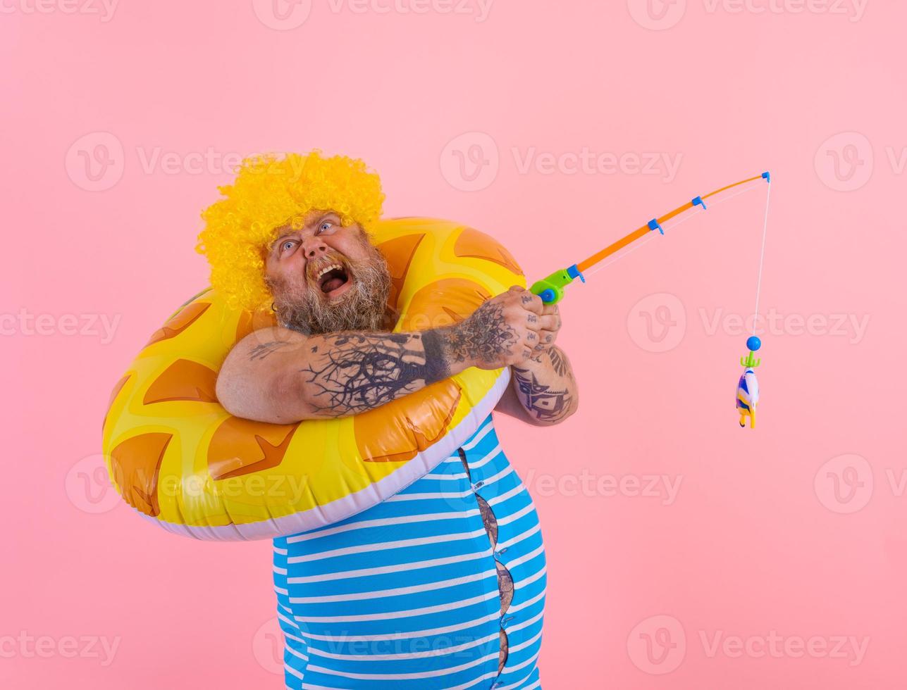 Fat stressed man with wig in head plays with the fishing rod photo