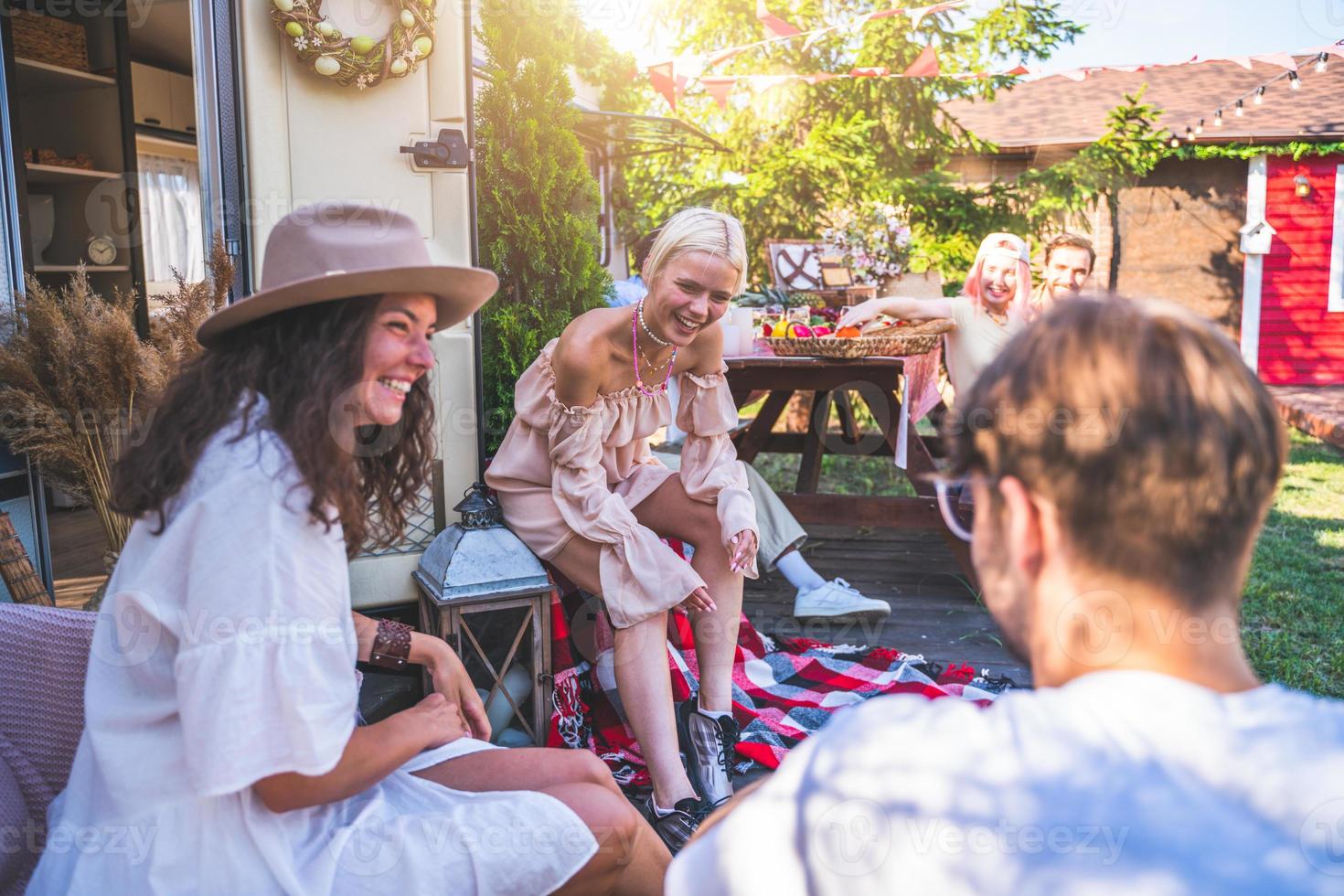 Friends have a picnic with a camper in a green meadow photo