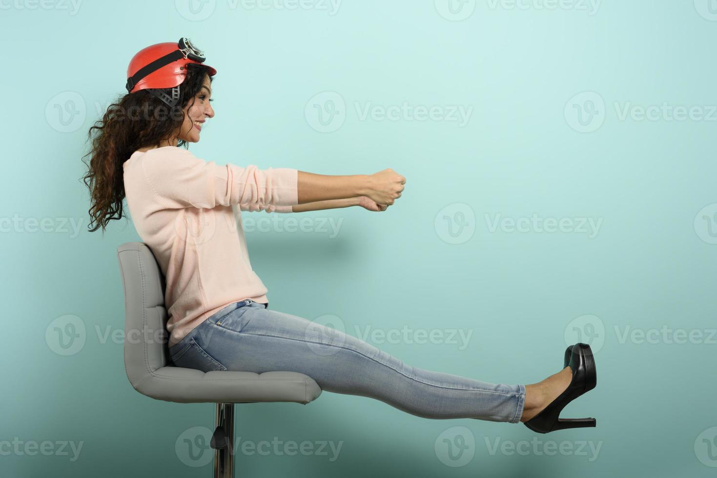 Woman with red helmet thinks to drive a fast car. cyan background. photo