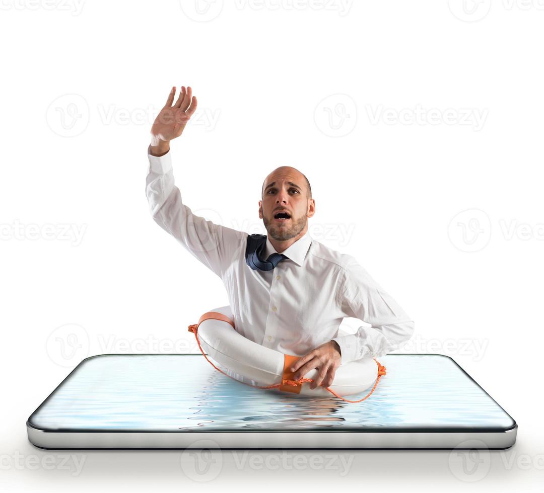 Businessman with lifebelt risks drowning on the screen of a smartphone photo