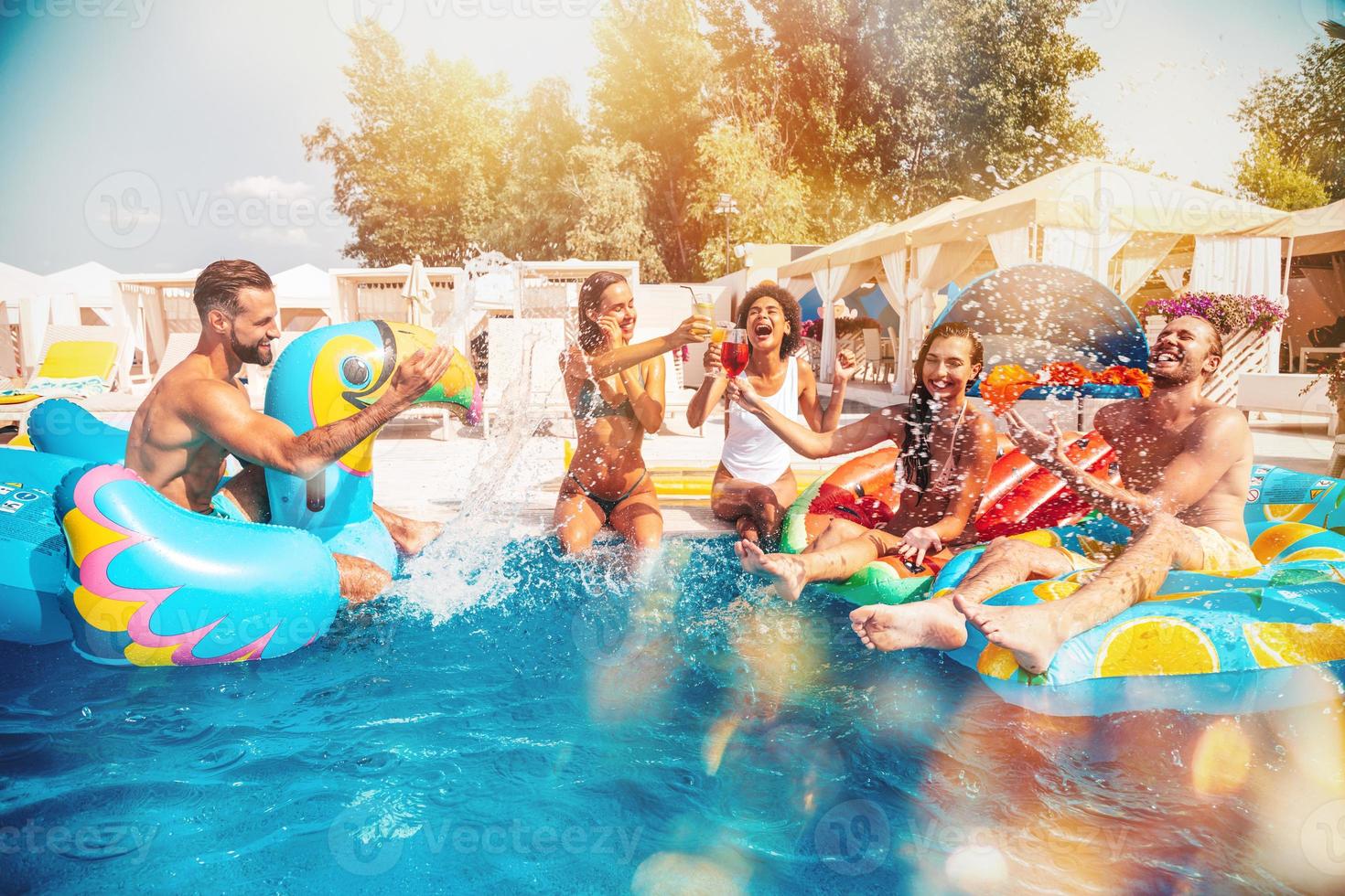 Group of friends in swimsuit enjoy in a swimming pool photo