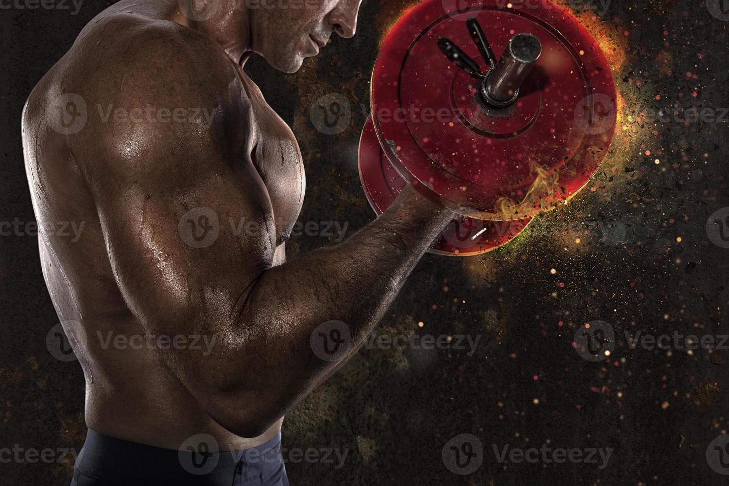 Athletic man training biceps at the gym with fire effect photo