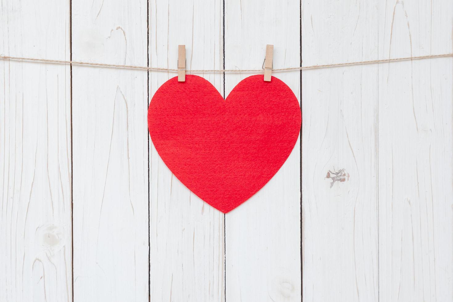 Red heart hanging on white wood  background with copy space. photo