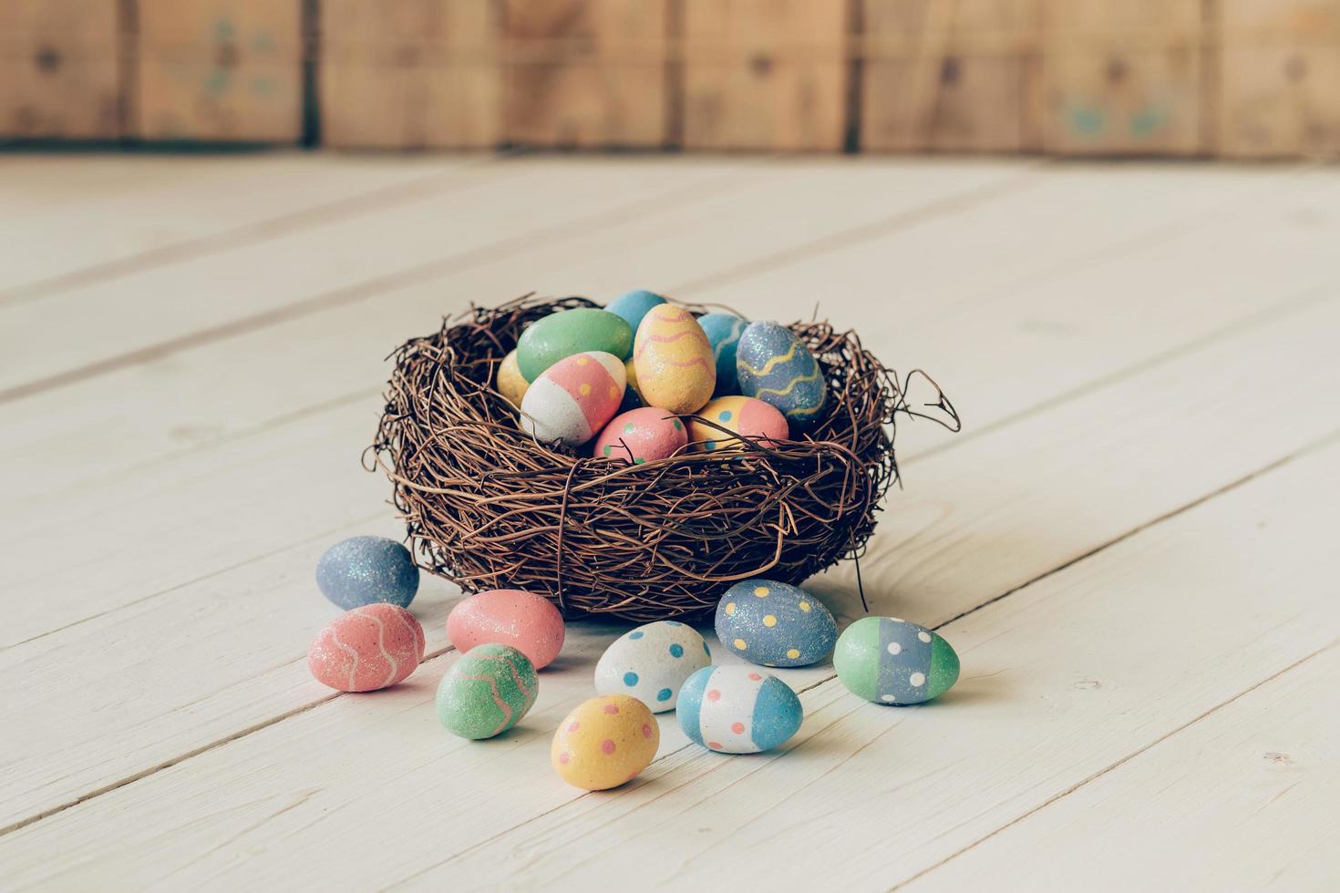 Colorful easter eggs in the nest on wood table background. photo