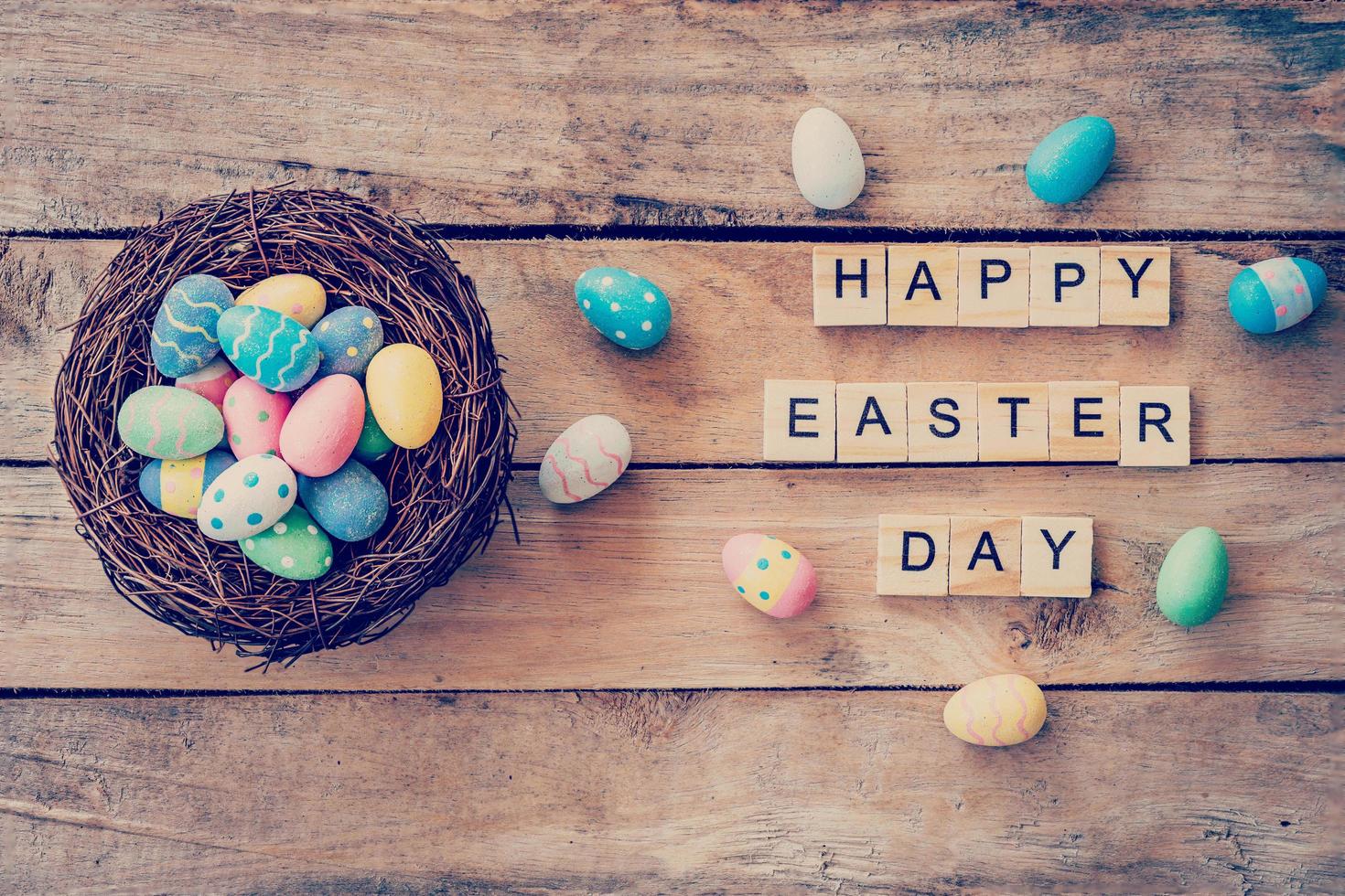 Colorful easter egg in the nest and wooden text of Happy Easter Day on wood background with space photo