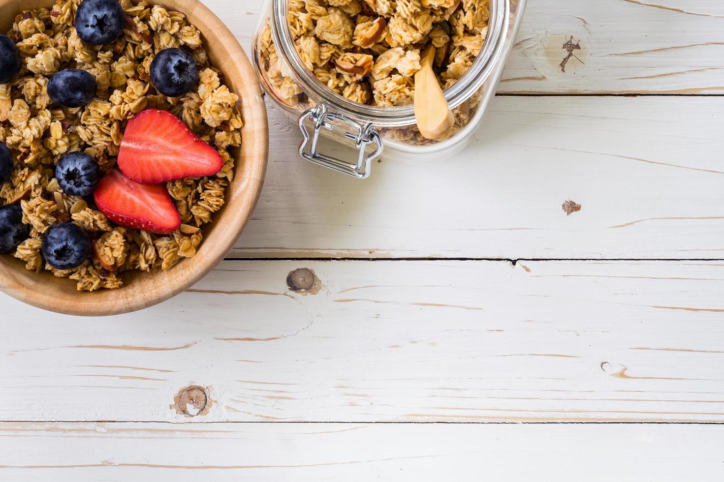 Homemade granola and fresh berries on wood table with space. photo