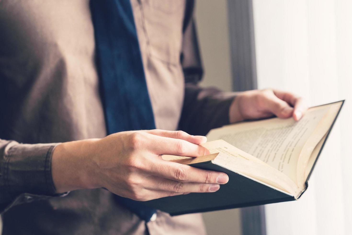 Business man hand holding book and reading at window. photo