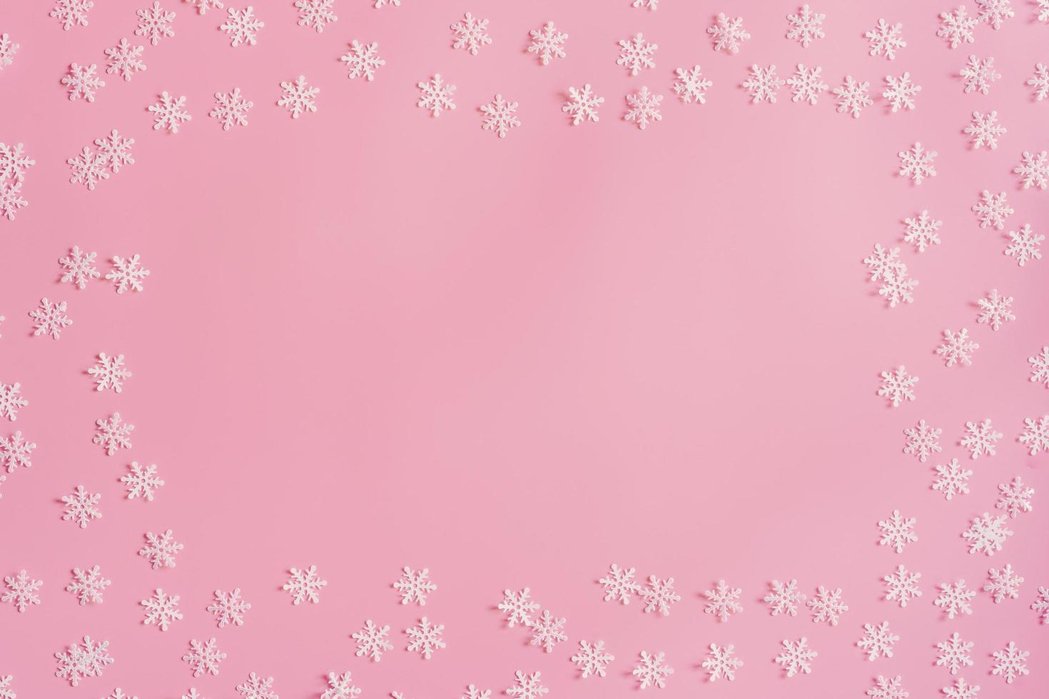Top view Christmas snowflake border frame on pink background. Xmas minimal texture with copy space. photo