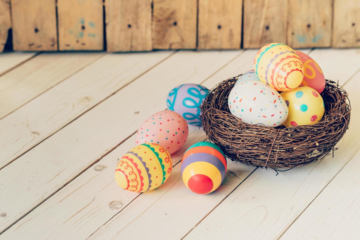 Colorful easter eggs in the nest on wood table background. photo