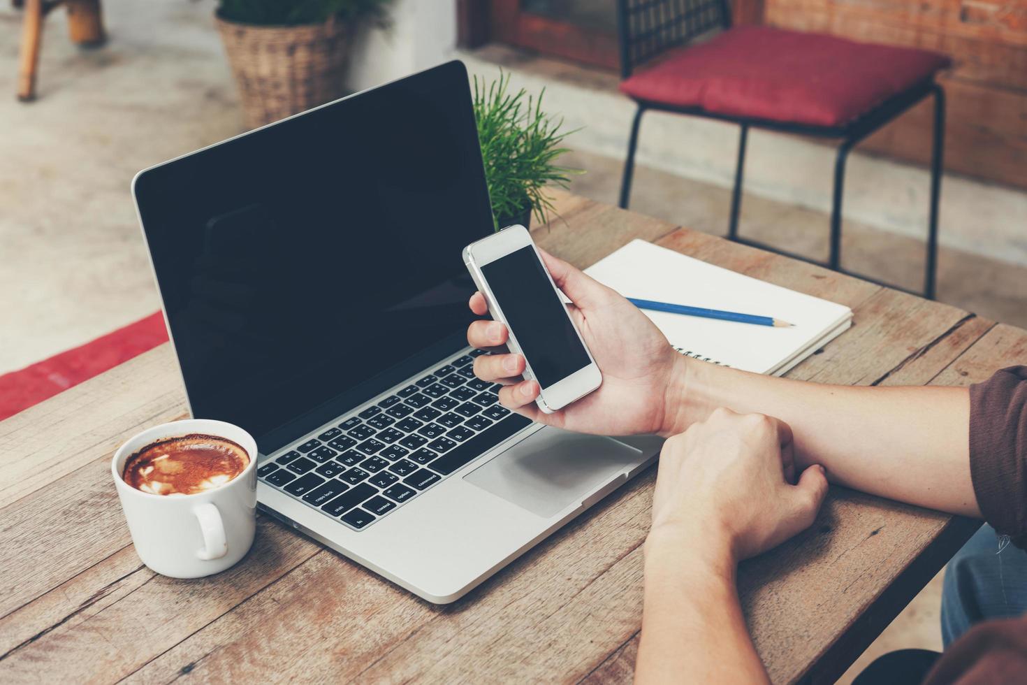 Business man holding phone and laptop on wooden table. Vintage toned. photo