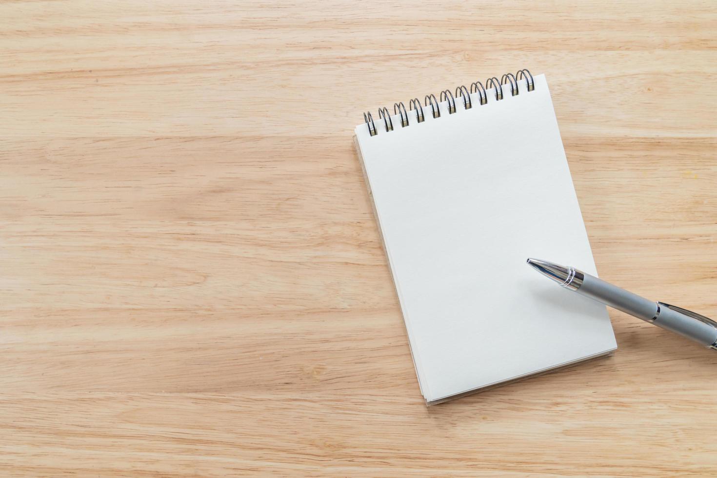 Top view of blank notebook with pen and natural light on wooden table. photo