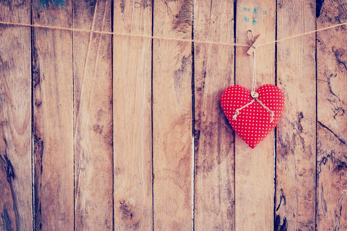 Heart fabric hanging on clothesline and wood background with space. photo