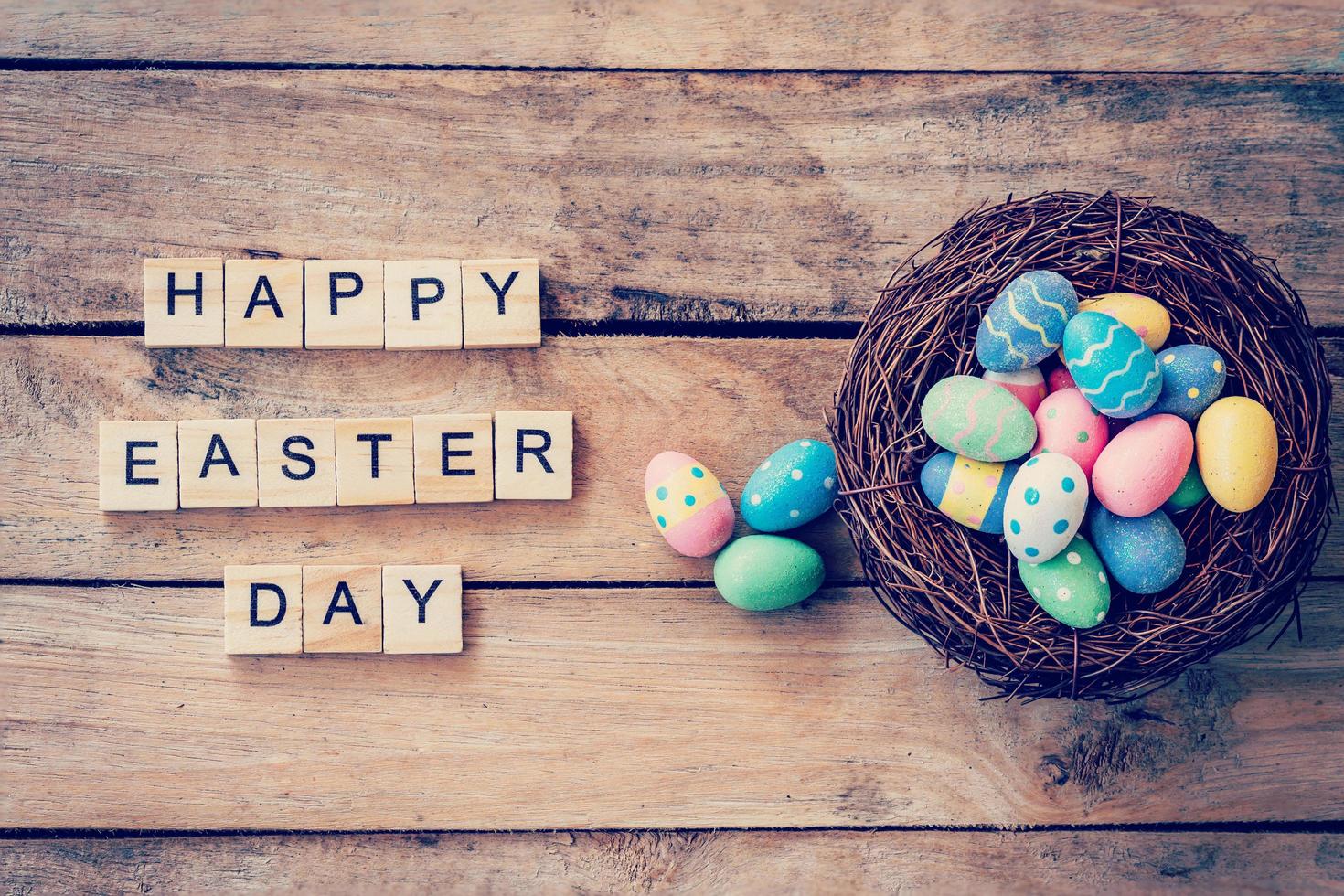 Colorful easter egg in the nest and wood text for Happy Easter Day on wood background with space photo