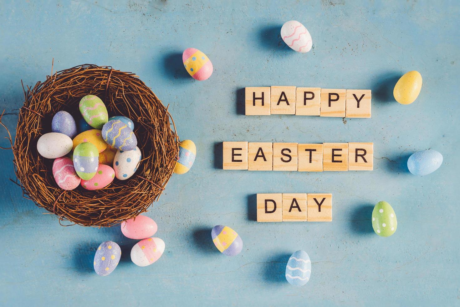 Colorful easter egg in the nest and wood text Happy Easter Day on blue pastel color wood background with space. photo