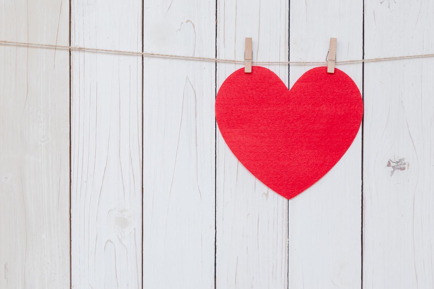 Red heart hanging on white wood  background with copy space. photo