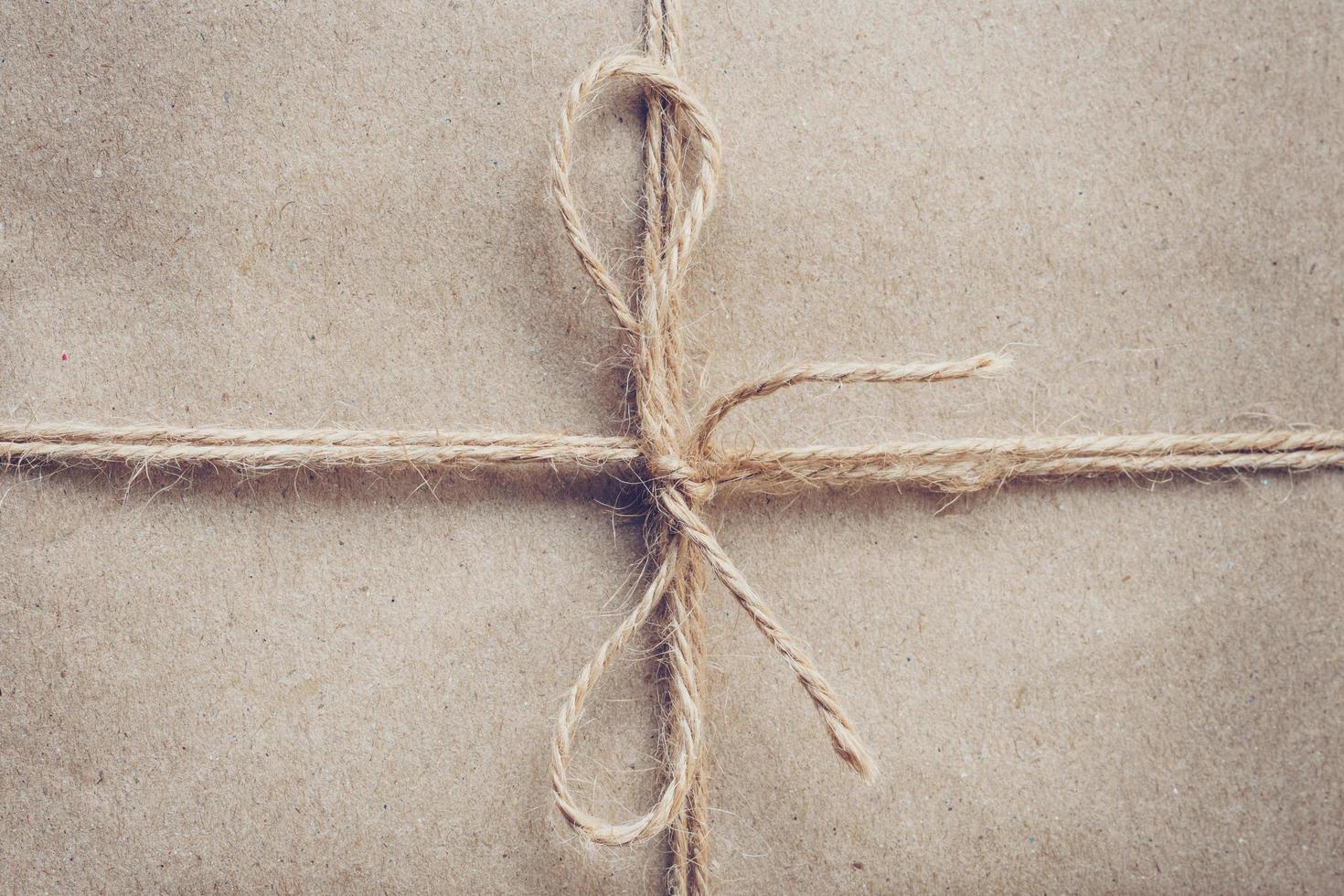 String or twine tied in a bow on brown kraft paper texture. photo