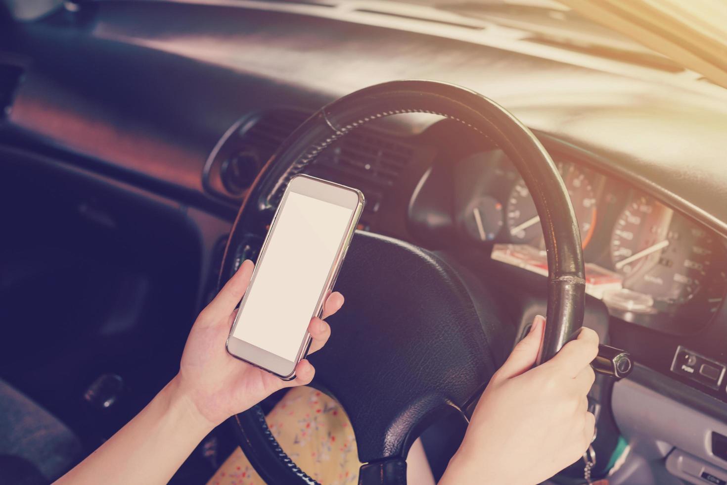 woman driver hands holding steering wheel driving and holding phone in a car photo