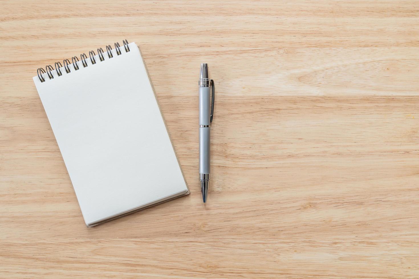 Top view of blank notebook with pen and natural light on wooden table. photo