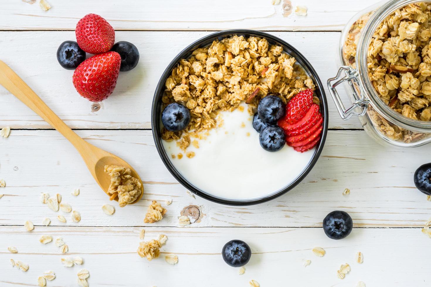 bowl of granola with yogurt, fresh berries, strawberry on wood table. photo