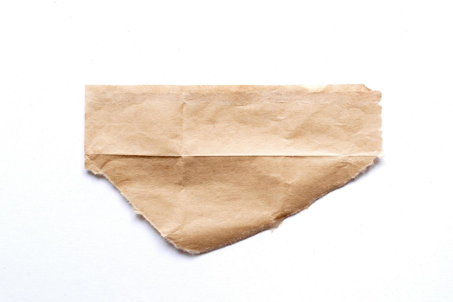 Close up of a ripped piece of brown paper on white background photo