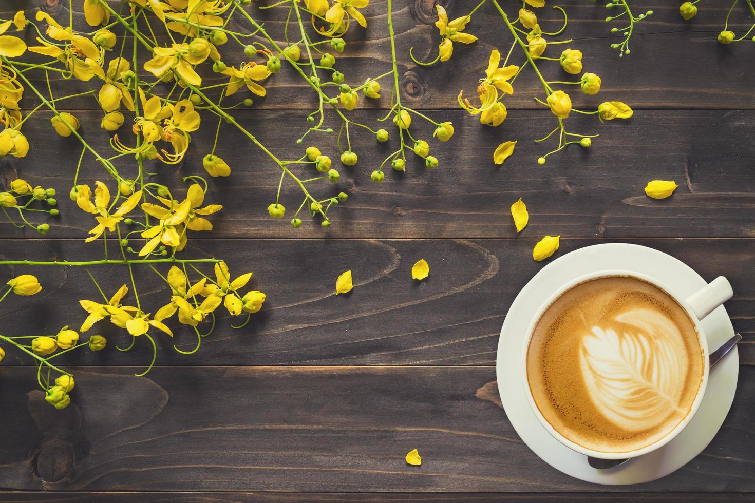 Coffee cup and Yellow flower on wooden background with space with vintage toned. photo