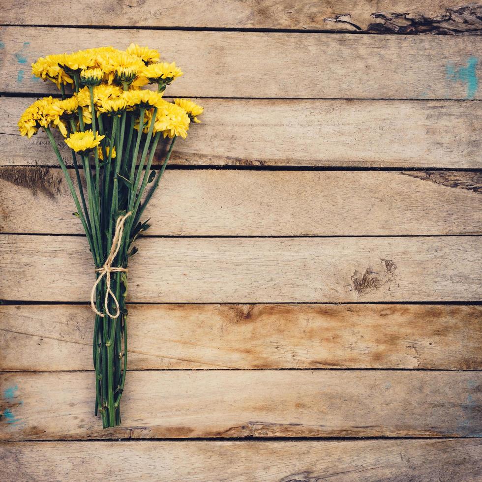 Yellow flowers of bouquet, top view on wooden background texture with copy space photo