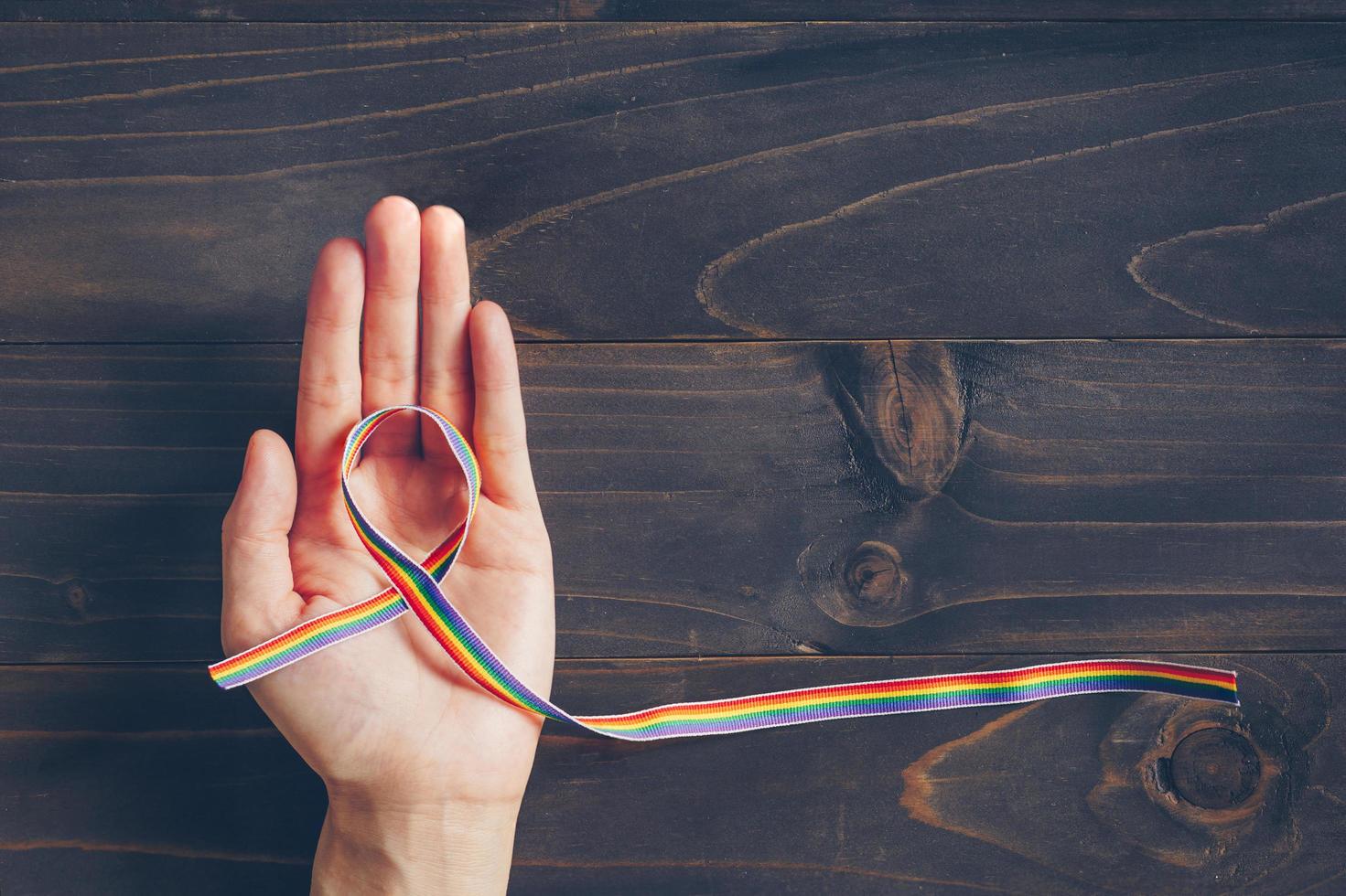 arco iris cinta conciencia en mano humano para lgbt concepto en de madera antecedentes. foto