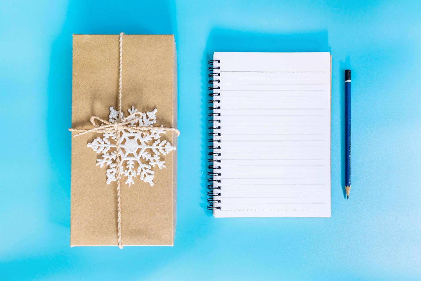 top view brown gift box and notebook paper for new year on blue pastel color. photo