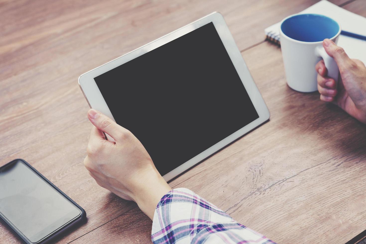 Hand woman using tablet computer on wooden table with Vintage toned. photo