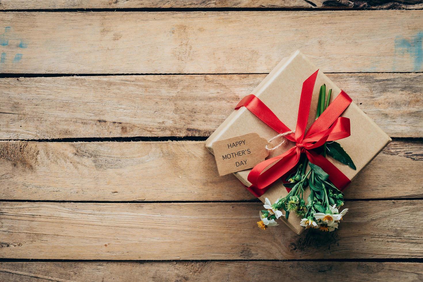 Brown gift box and flower on wood table present, mother's day concept. photo