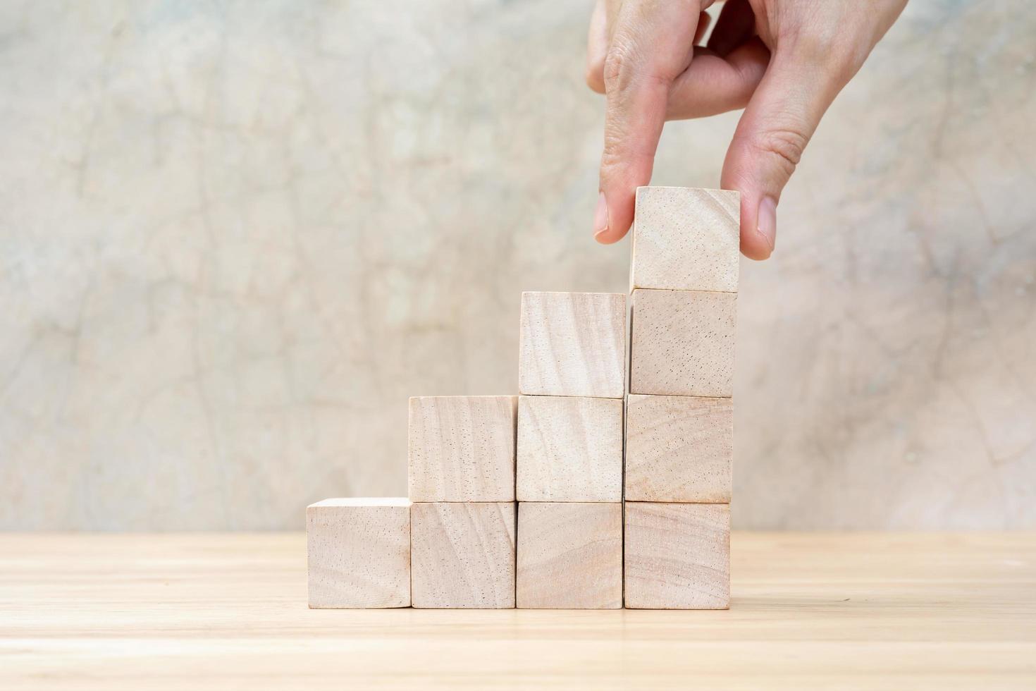 Hand arranging wood block stacking as step stair on wooden table. Business concept for growth success process. Copy space photo