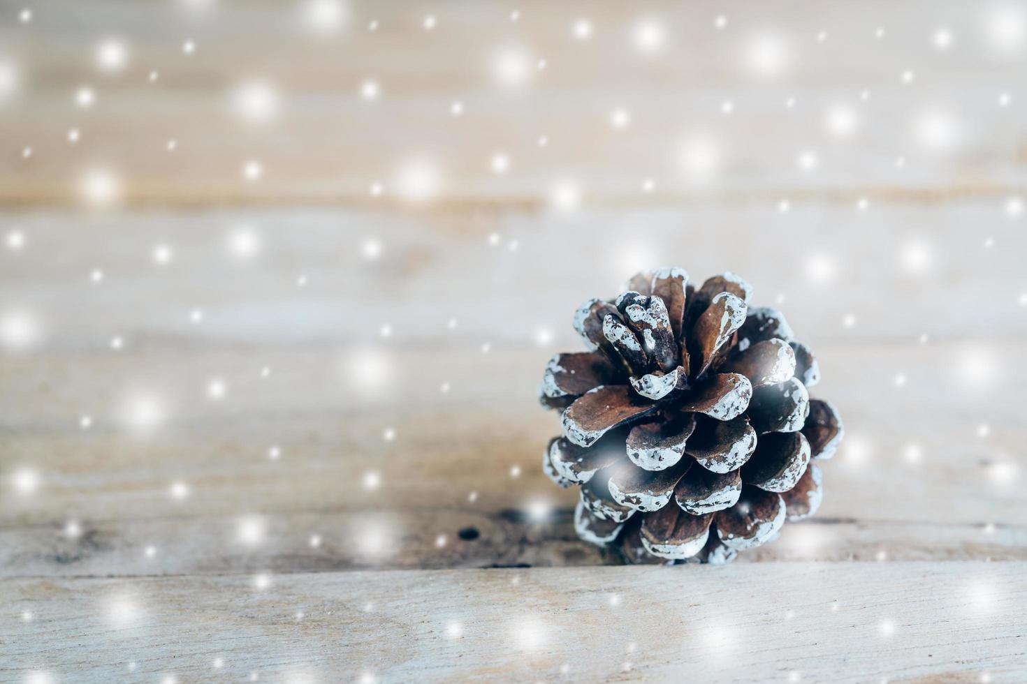 Pine cone and white snow on wood table background with space. photo